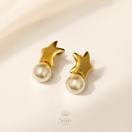 Aretes dorados en forma de estrella con perla sobre fondo crema elegante de Sisu Jewelry.
