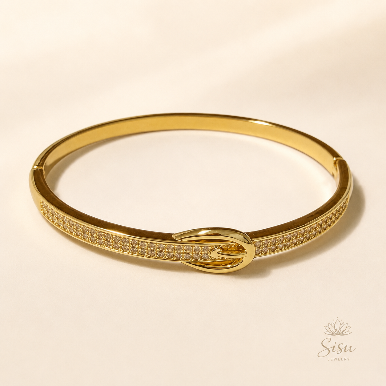 Brazalete dorado con detalles brillantes y cierre ovalado sobre fondo crema elegante de Sisu Jewelry.
