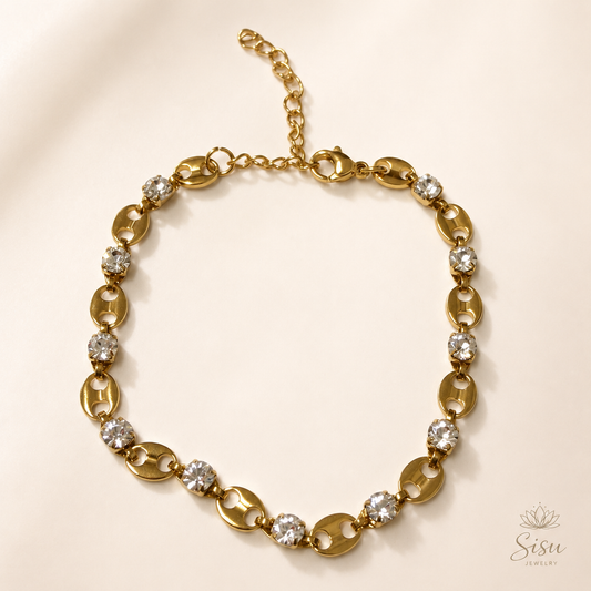 Pulsera dorada con cristales brillantes sobre fondo crema elegante de Sisu Jewelry.