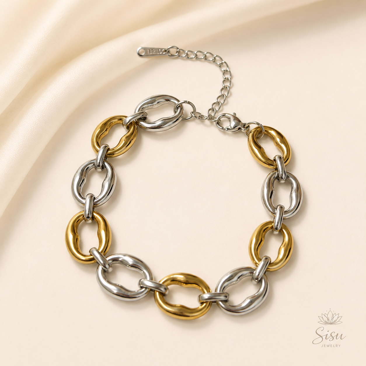 Pulsera de eslabones dorados y plateados sobre fondo crema elegante de Sisu Jewelry.
